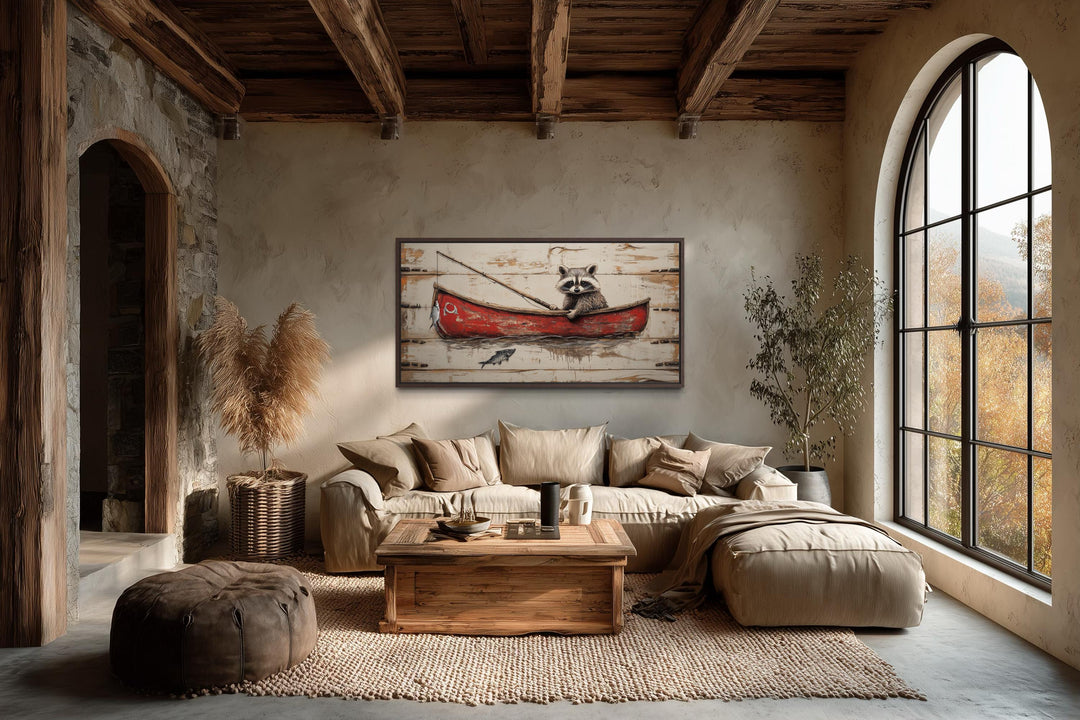 Horizontal wall art of a raccoon fishing in a red boat hangs in a rustic, cozy living room.