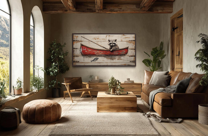 Whimsical raccoon fishing wall art in a red boat hangs in a rustic, cozy living room.