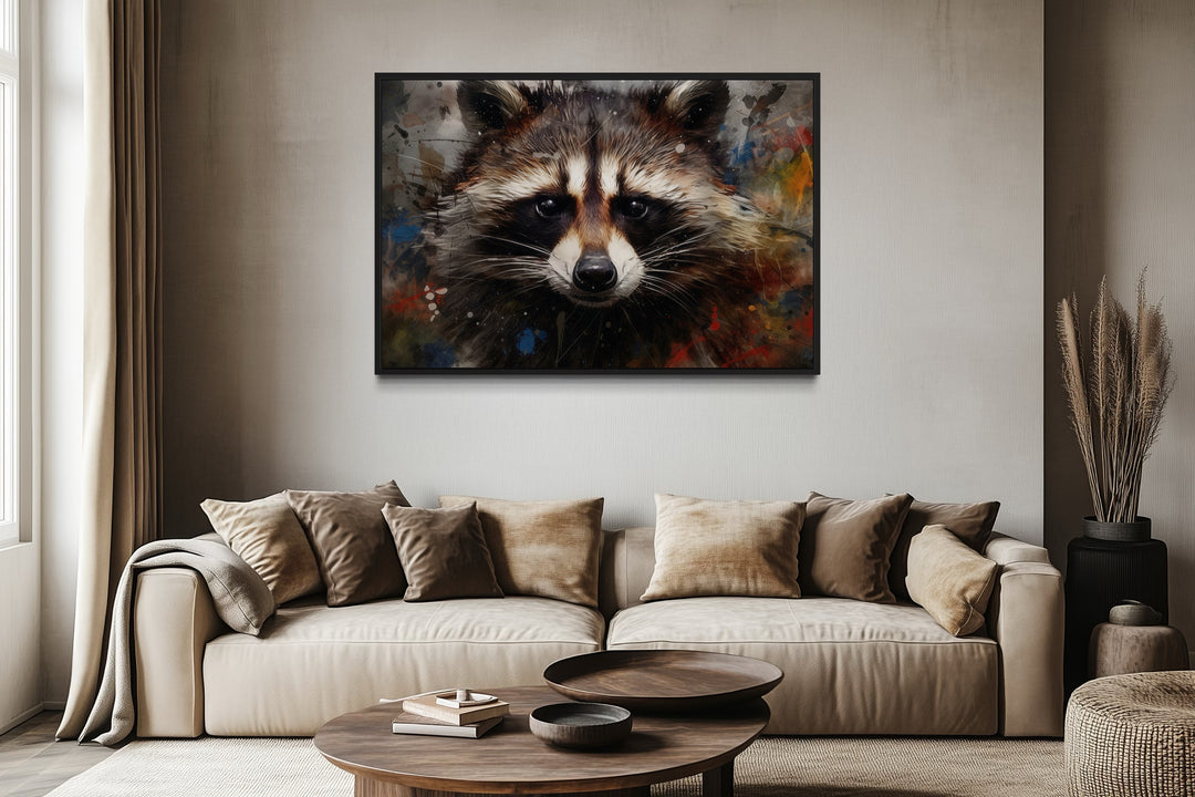 A framed modern pop art canvas of a raccoon portrait hangs above a neutral-toned sofa.