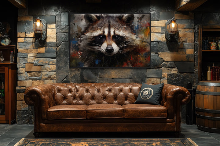 Framed raccoon pop art canvas on a stone wall above a brown leather tufted sofa in a rustic room.