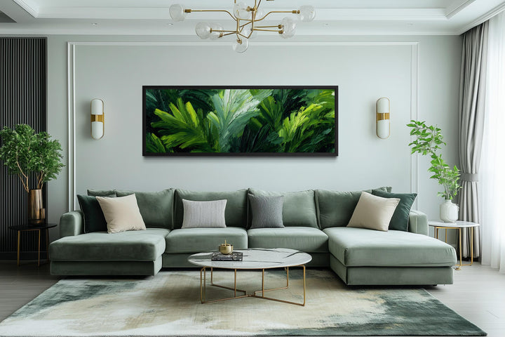 A long horizontal canvas print of lush green rainforest leaves hangs above a modern green sofa.