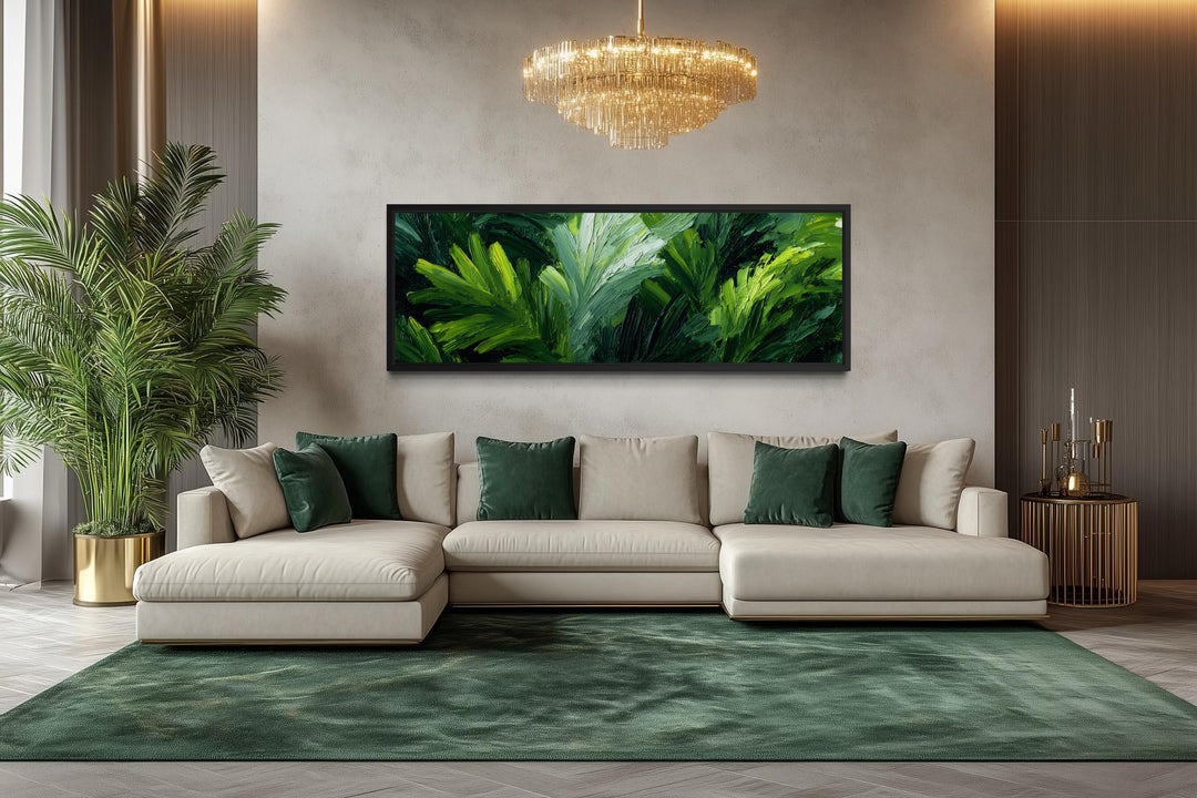 A long horizontal canvas print of lush green rainforest leaves hangs above a modern cream sofa.