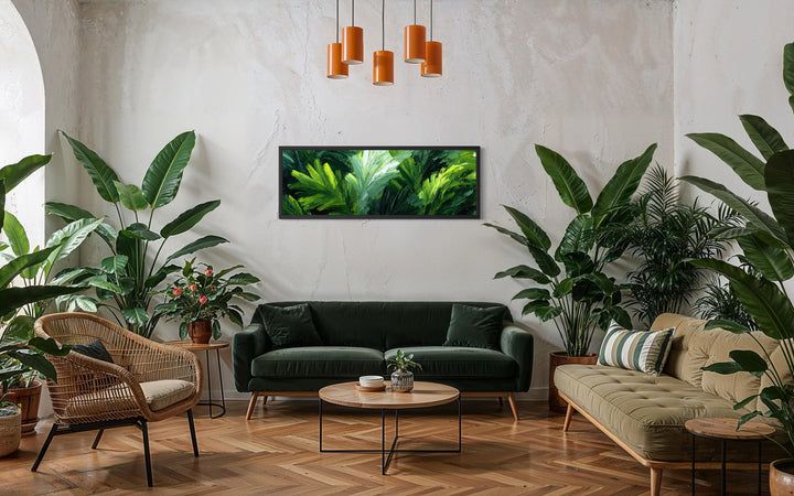 Panoramic rainforest jungle leaves canvas print displayed above a green sofa in a botanical room.
