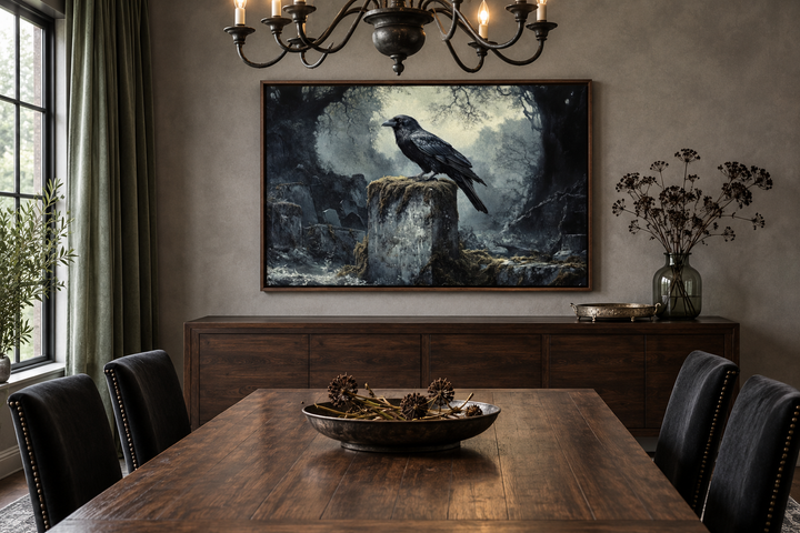 Framed gothic wall art of a black raven on a tombstone in a cemetery above a dining room sideboard.