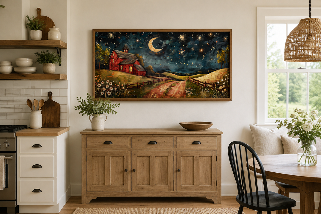 Framed wall art of a red barn under a crescent moon and starry night sky above a wooden sideboard.