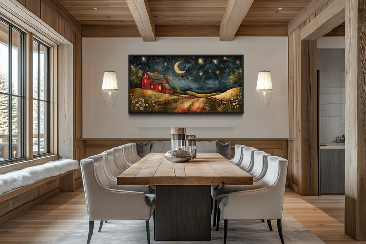Red barn on a farm at night under stars and a crescent moon wall art in a rustic dining room.