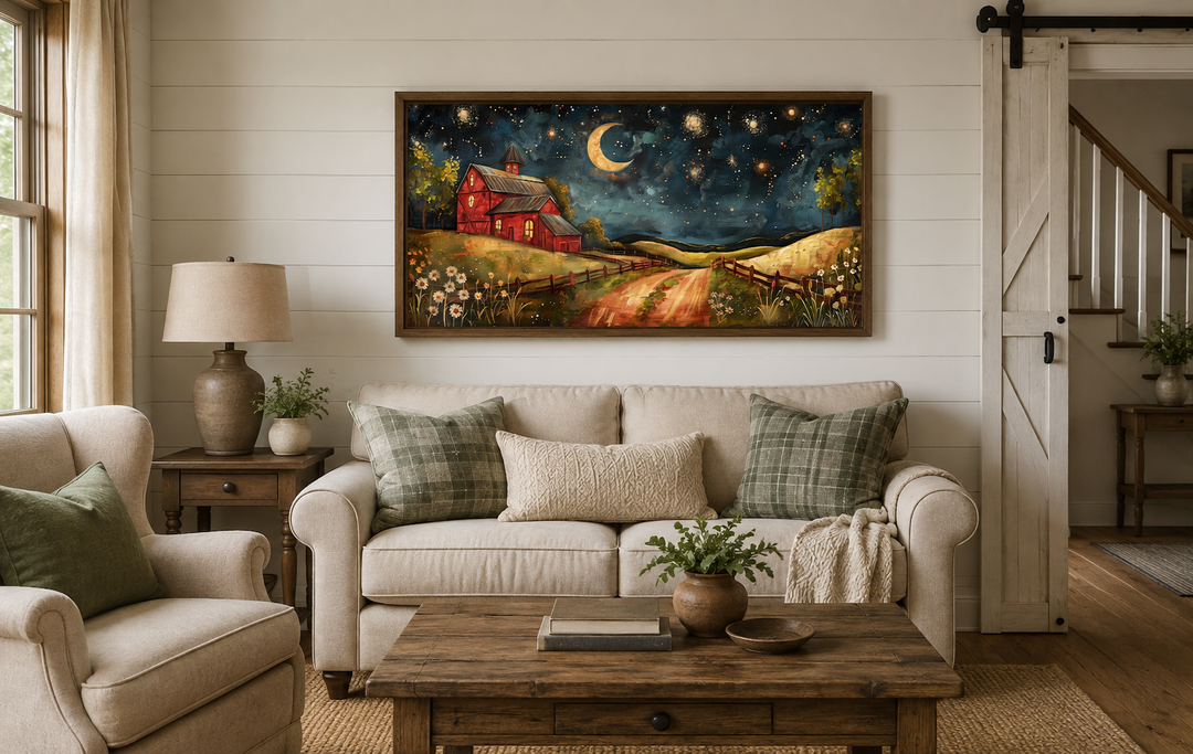 Framed wall art of a red barn under a starry night sky with a crescent moon above a beige sofa.