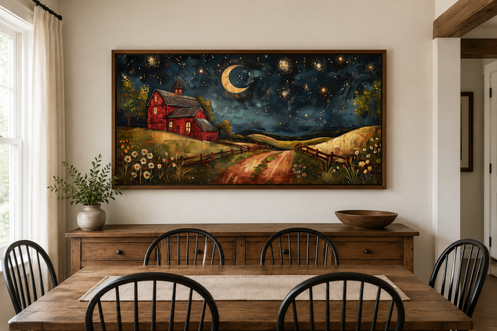 Framed wall art of a red barn under a crescent moon and starry sky above a wooden sideboard.