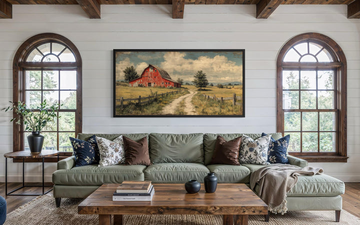 Large horizontal canvas print of a red barn landscape in a rustic farmhouse living room.
