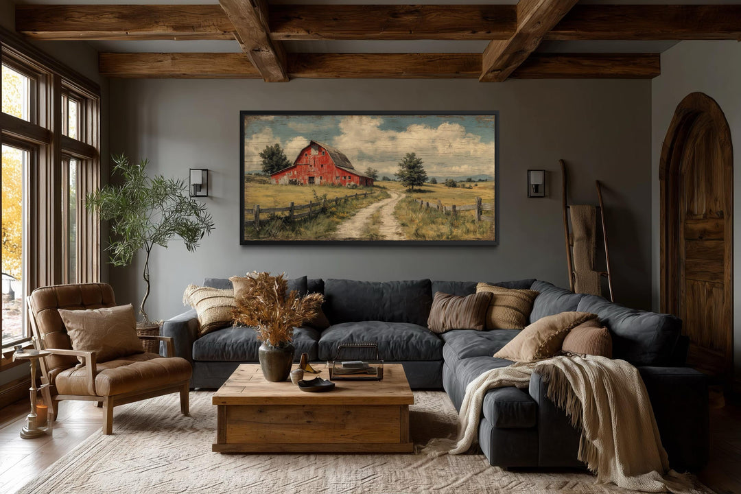 Large horizontal canvas print of a rustic red barn landscape in a farmhouse living room.