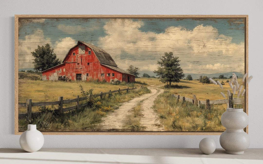 Large horizontal canvas print of a rustic red barn in a landscape, framed in light wood.