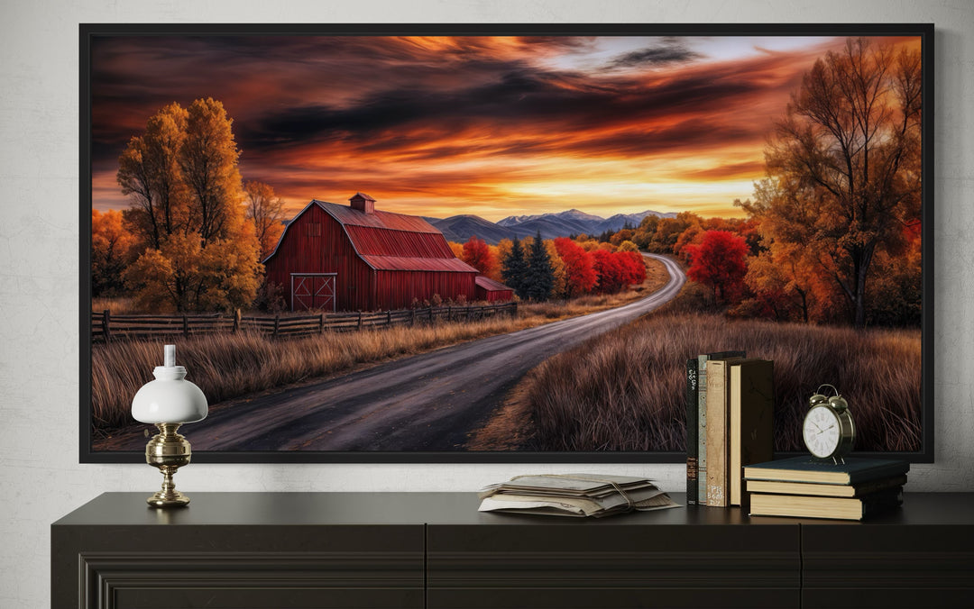 Framed red barn wall art depicting a rustic fall landscape at sunset above a dark wood dresser.