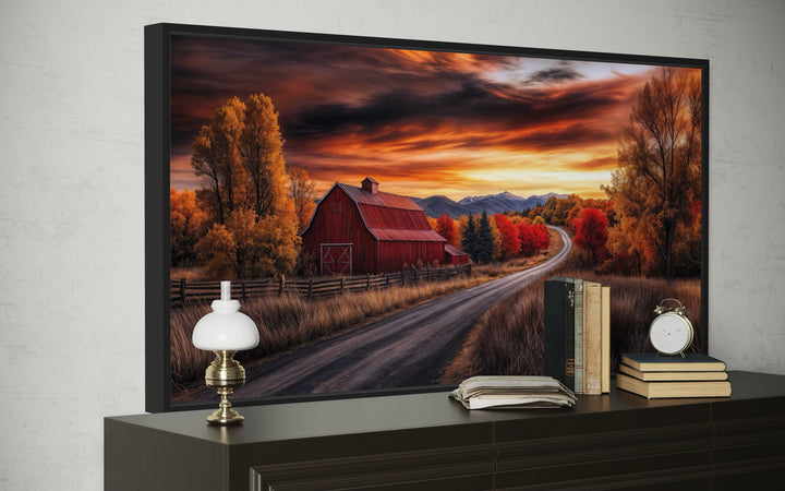 Framed canvas wall art of a red barn on a country road during a vibrant autumn sunset.