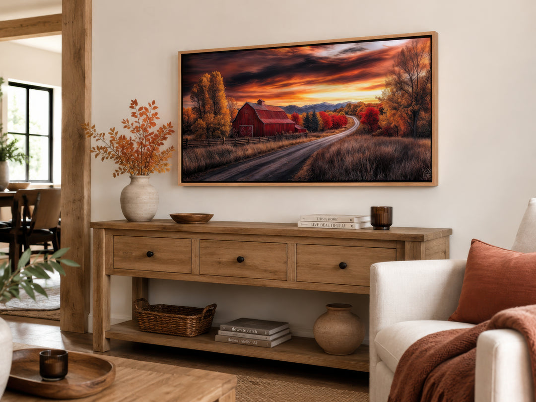 Framed red barn wall art with fall foliage and sunset over a console table in a farmhouse living room