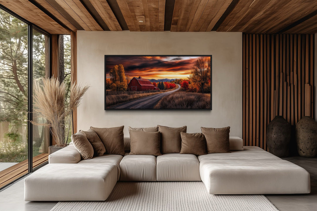 Red barn wall art in a rustic fall landscape hanging above a modern sofa in a farmhouse living room.