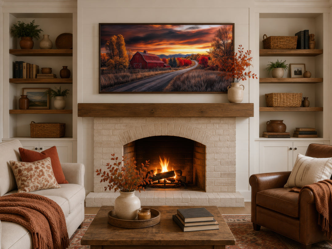 Red barn wall art in a rustic fall landscape displayed above a fireplace in a cozy living room.