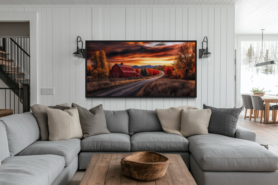 Red barn wall art featuring a rustic fall landscape at sunset above a gray sectional sofa.