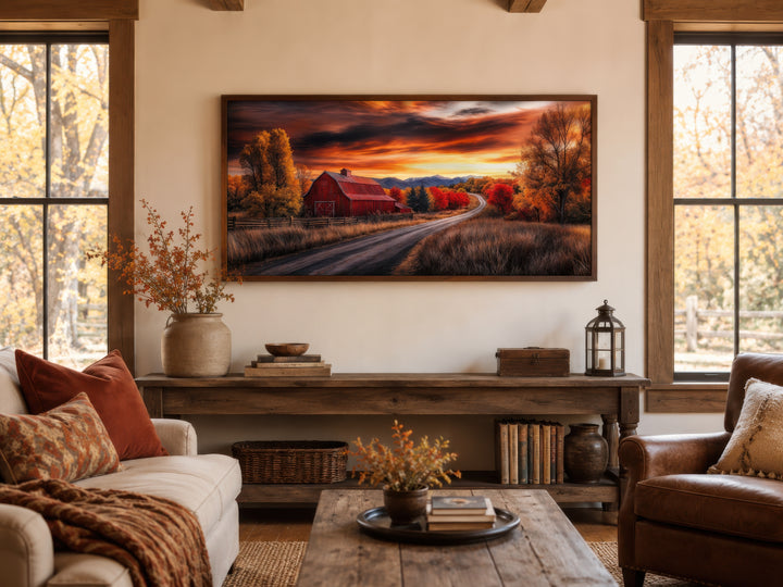 Framed red barn wall art in a rustic living room with fall foliage and sunset colors.