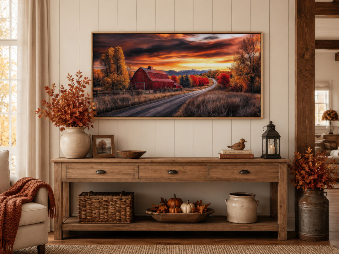 Red barn wall art in a rustic frame above a wooden console table with autumn farmhouse decor.