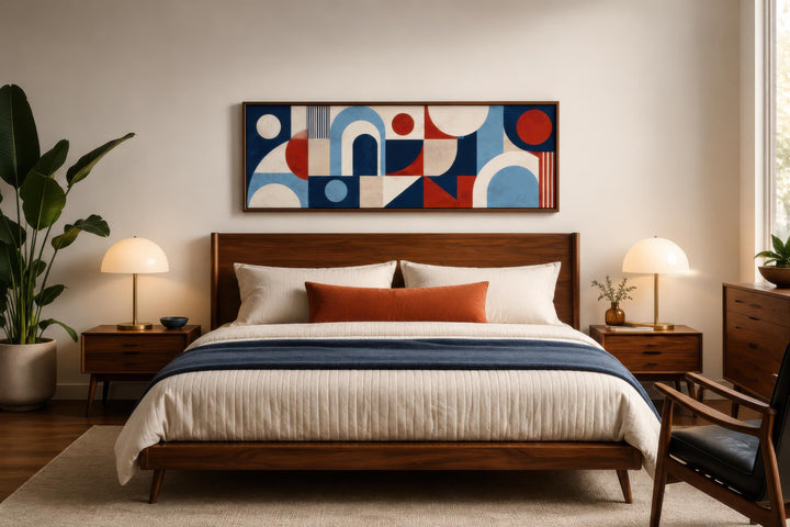 Long narrow Bauhaus wall art with red and blue geometric shapes above a mid-century modern bed.