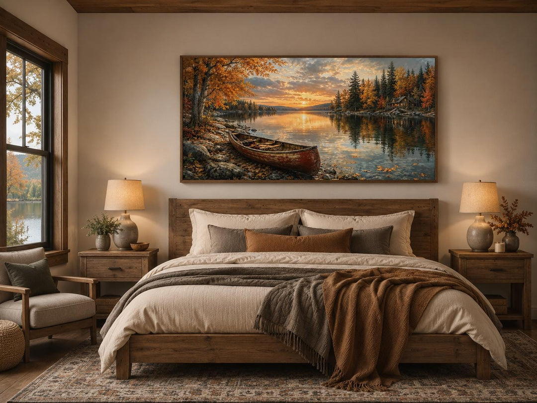 Red canoe on an autumn lake shore canvas wall art hanging above a rustic wooden bed.