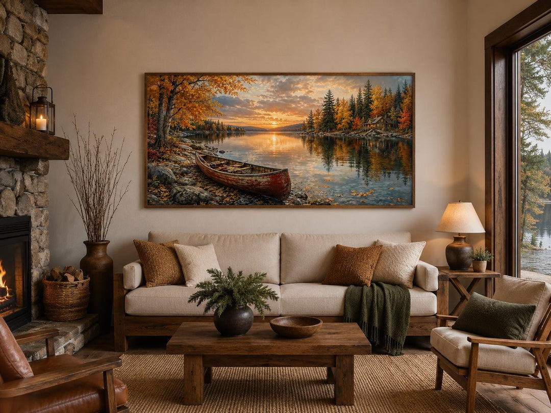 Red canoe on an autumn lake shore canvas wall art displayed above a sofa in a rustic living room.