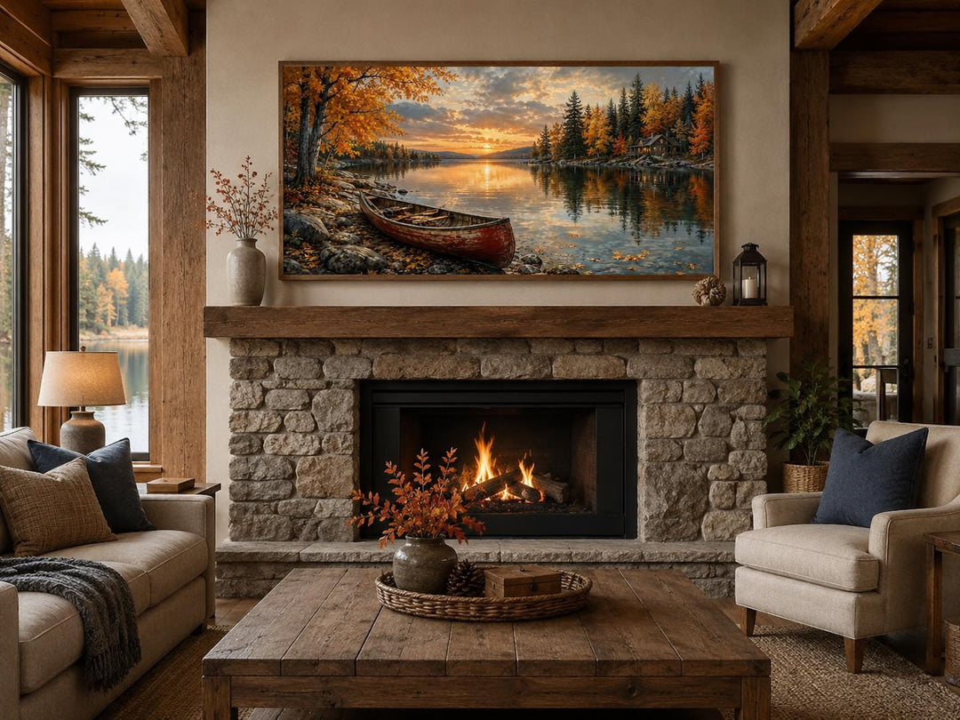 Red canoe on an autumn lake canvas wall art hanging above a stone fireplace in a rustic living room.