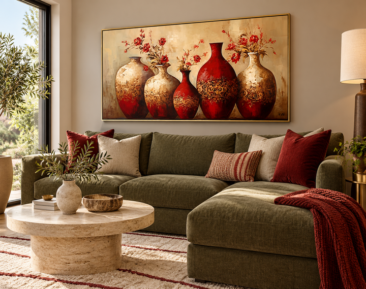 Framed canvas wall art featuring five ornate red and gold vases with red flowers above a green sofa.