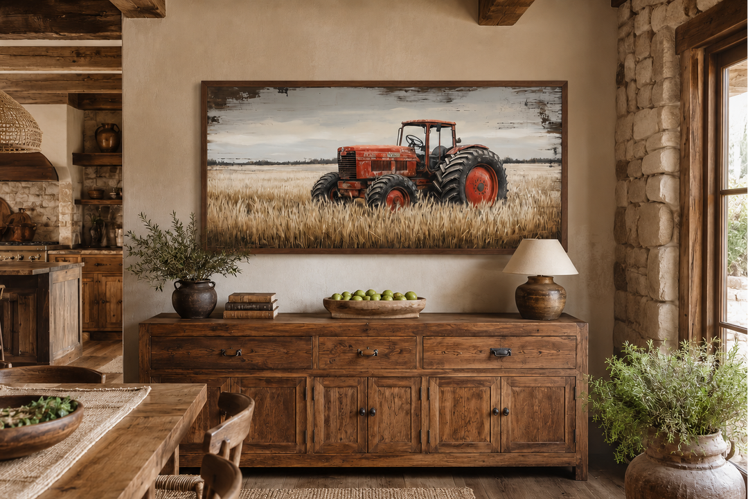 Framed rustic wall art of a vintage red tractor in a golden wheat field above a wooden sideboard.