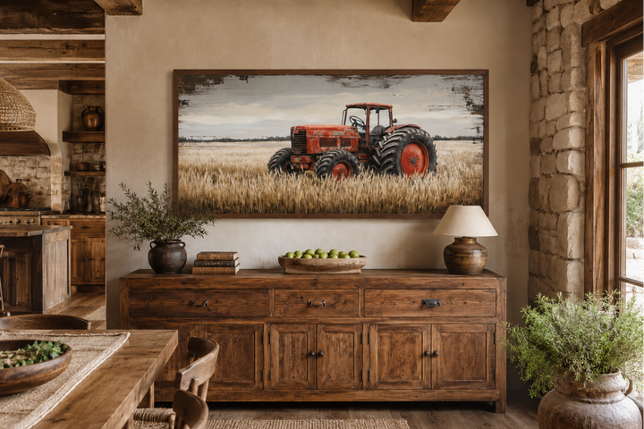 Framed rustic wall art of a vintage red tractor in a golden wheat field above a wooden sideboard.