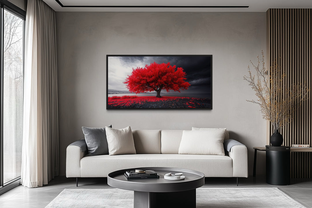 Framed canvas print of a vibrant red tree against a monochrome landscape in a modern living room.