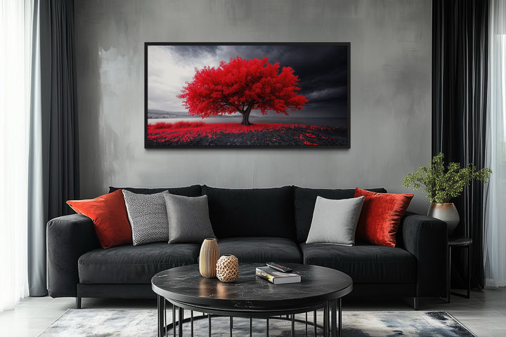 Framed canvas print of a vibrant red tree against a monochrome landscape in a modern living room.