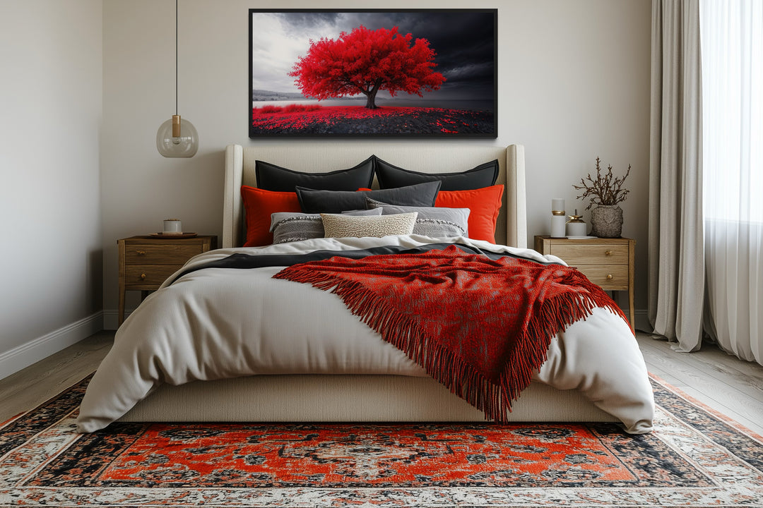 Framed canvas print of a vibrant red tree against a black and white landscape above a bed.