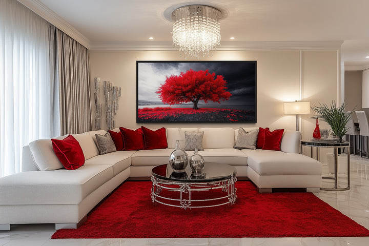 Framed canvas print of a vibrant red tree against a black and white landscape in a modern room.