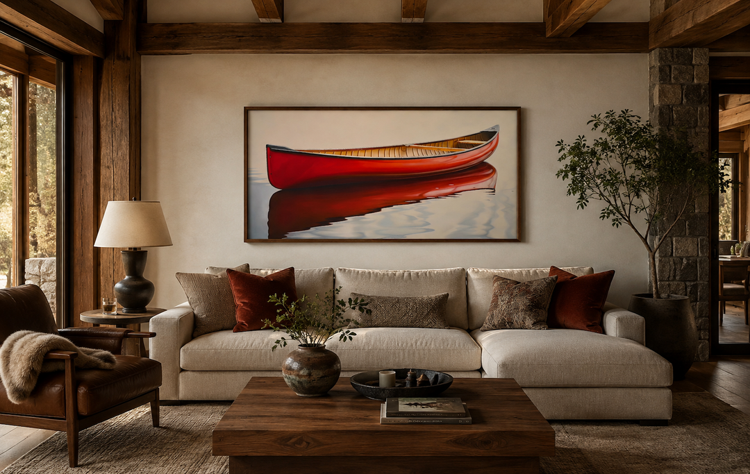 Framed canvas print of a red canoe on water, hanging above a sofa in a rustic cabin living room.