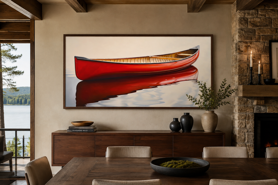 Framed canvas wall art of a red canoe reflected in water, displayed in a rustic cabin dining room.