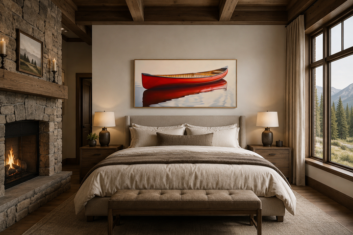 Framed canvas print of a red canoe on water hanging above a bed in a rustic cabin bedroom.