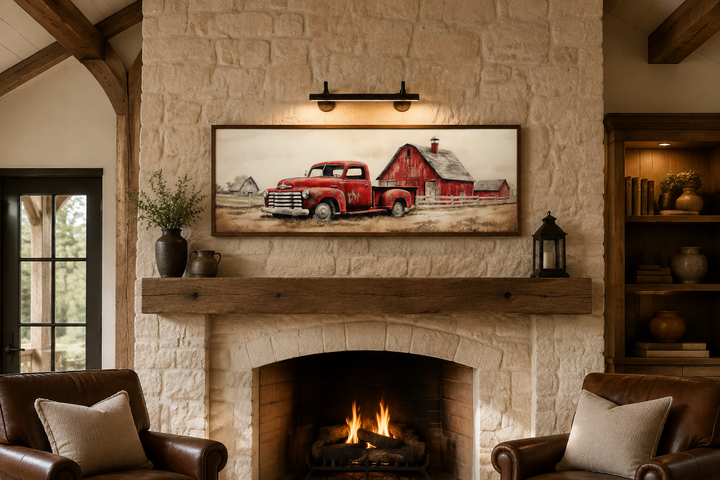 Red truck and barn painting on wood framed canvas wall art hanging above a stone fireplace mantel.