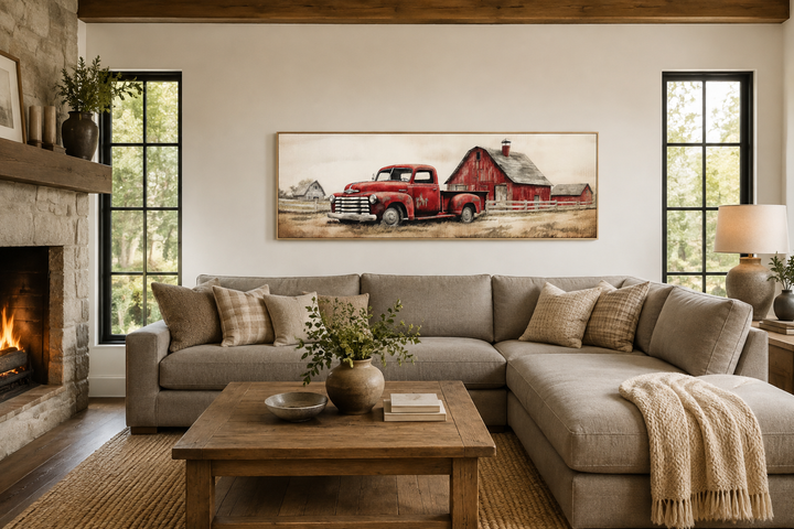Red truck and barn painting on wood framed canvas wall art above a neutral sectional sofa.