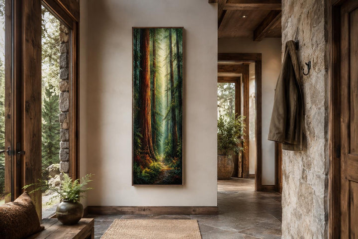 Tall narrow vertical canvas art of a redwood forest hanging in a rustic hallway with stone walls.
