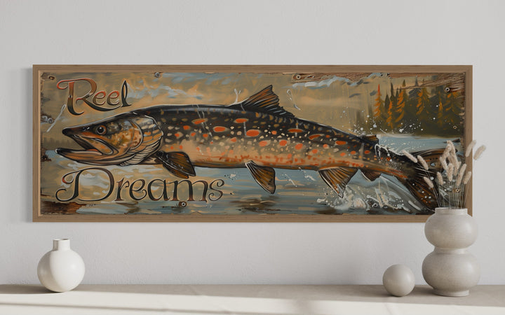 Framed canvas wall art of a pike fish with 'Reel Dreams' text in a rustic lodge style.