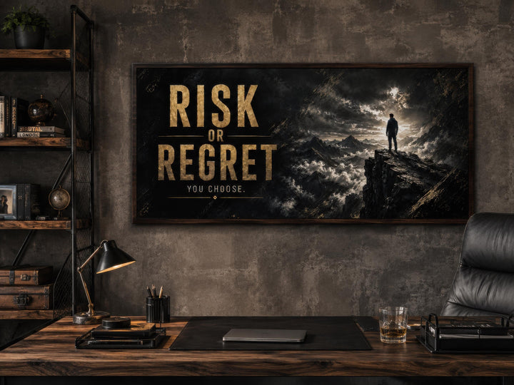 Risk or Regret motivational wall art in gold lettering above a dark office desk with a laptop.