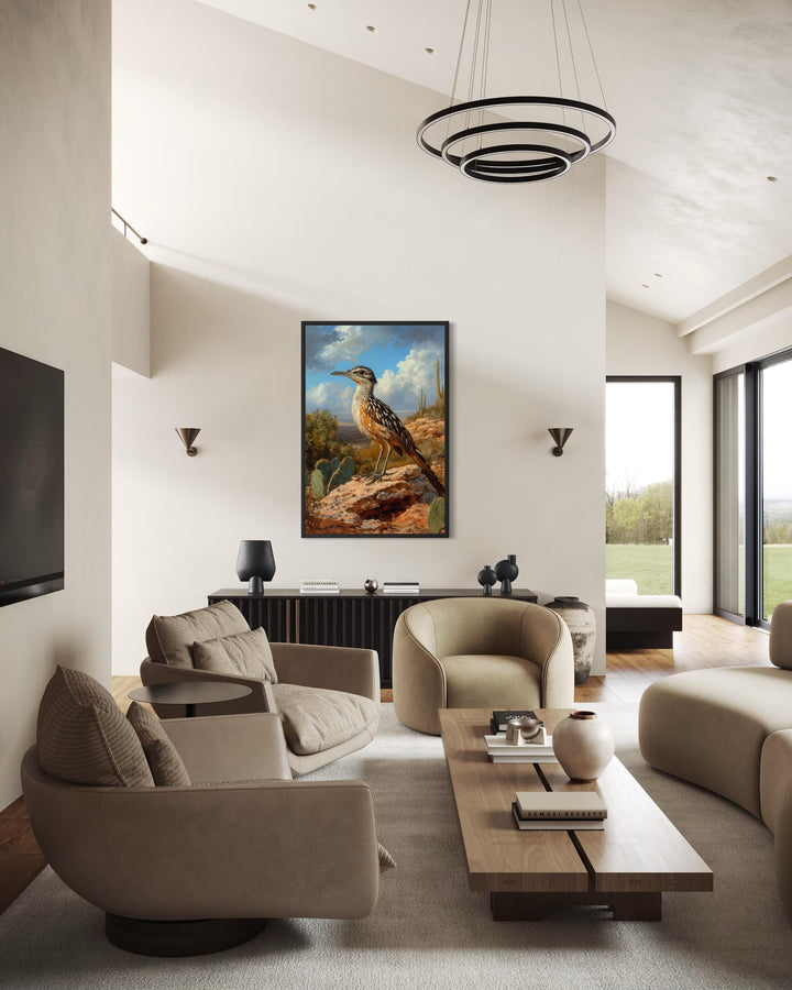 A framed canvas print of a roadrunner perched on a rock in a desert landscape hangs in a modern room.