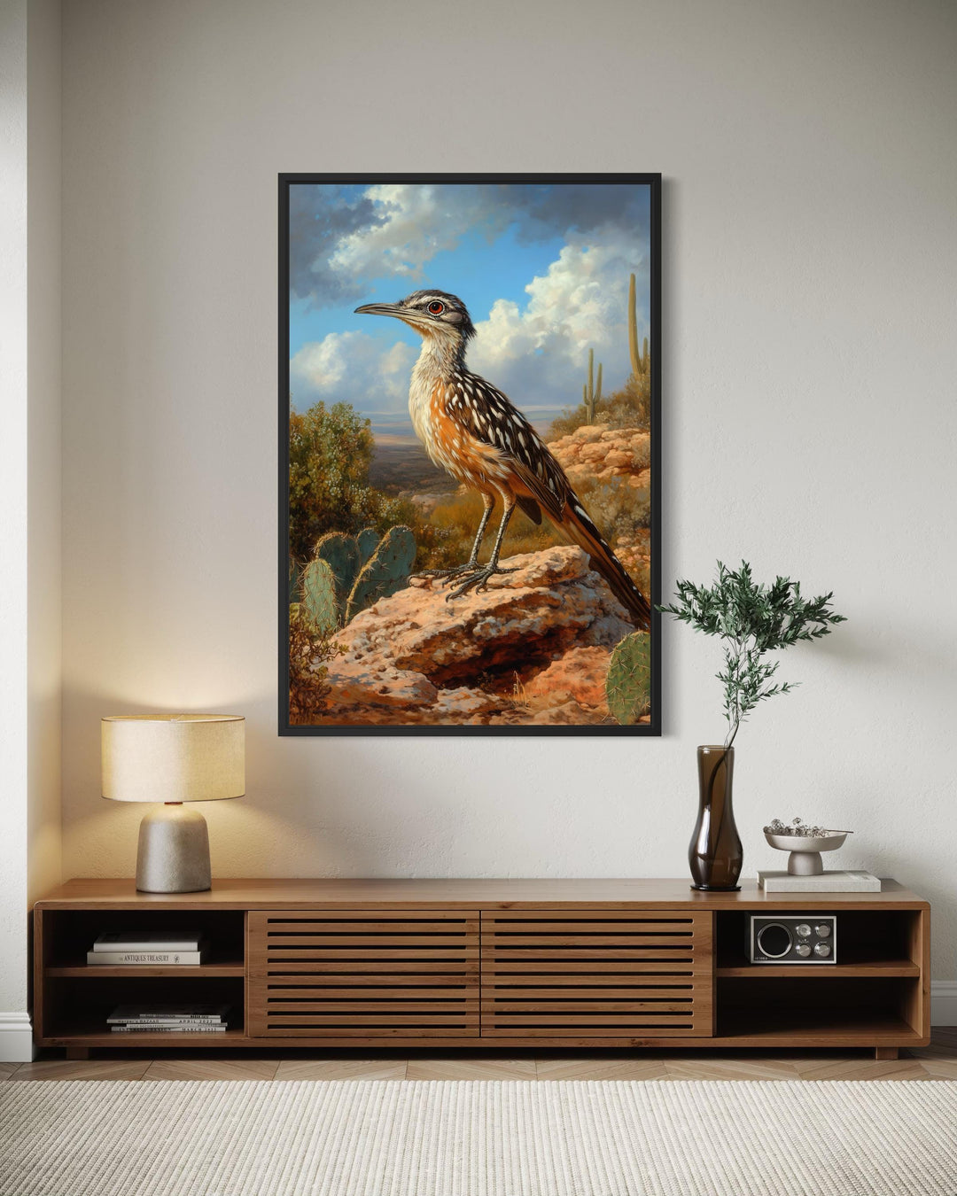 A framed canvas print of a roadrunner in a desert landscape hangs above a modern wooden console.