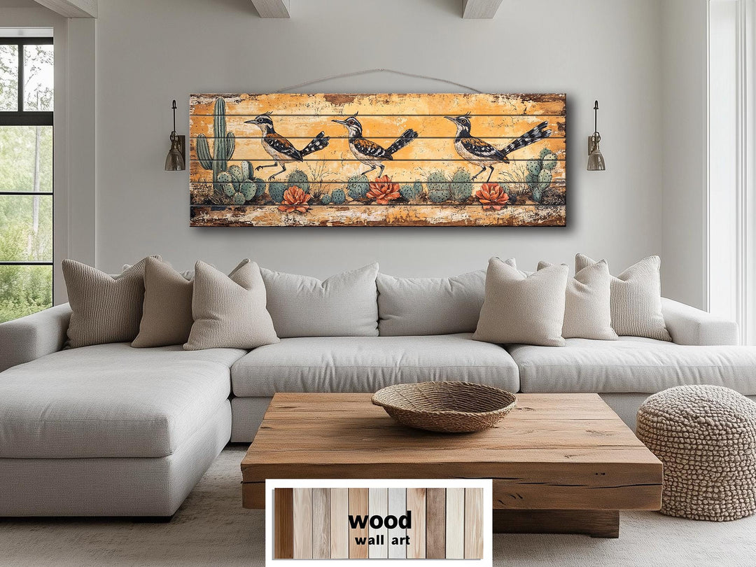 Roadrunners wood wall art featuring a distressed desert scene with cacti above a living room sofa.