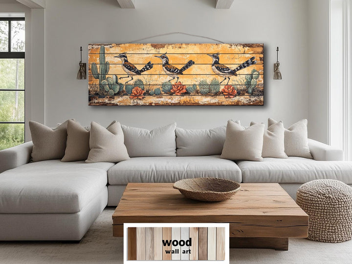 Roadrunners wood wall art featuring a distressed desert scene with cacti above a living room sofa.