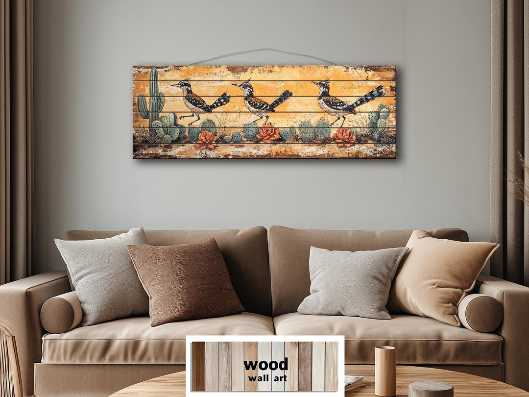 Horizontal wood wall art featuring three roadrunners in a desert scene above a tan sofa.