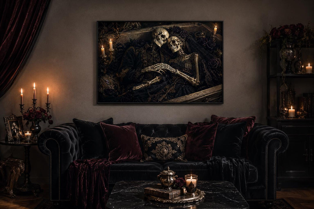 Romantic gothic canvas art of two skeletons embracing in an ornate coffin above a black sofa.