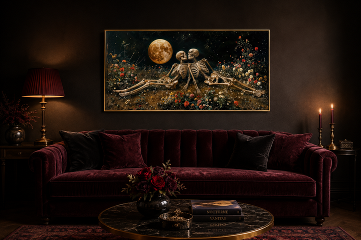 Gothic wall art of two skeletons in a flower meadow under a full moon above a velvet sofa.
