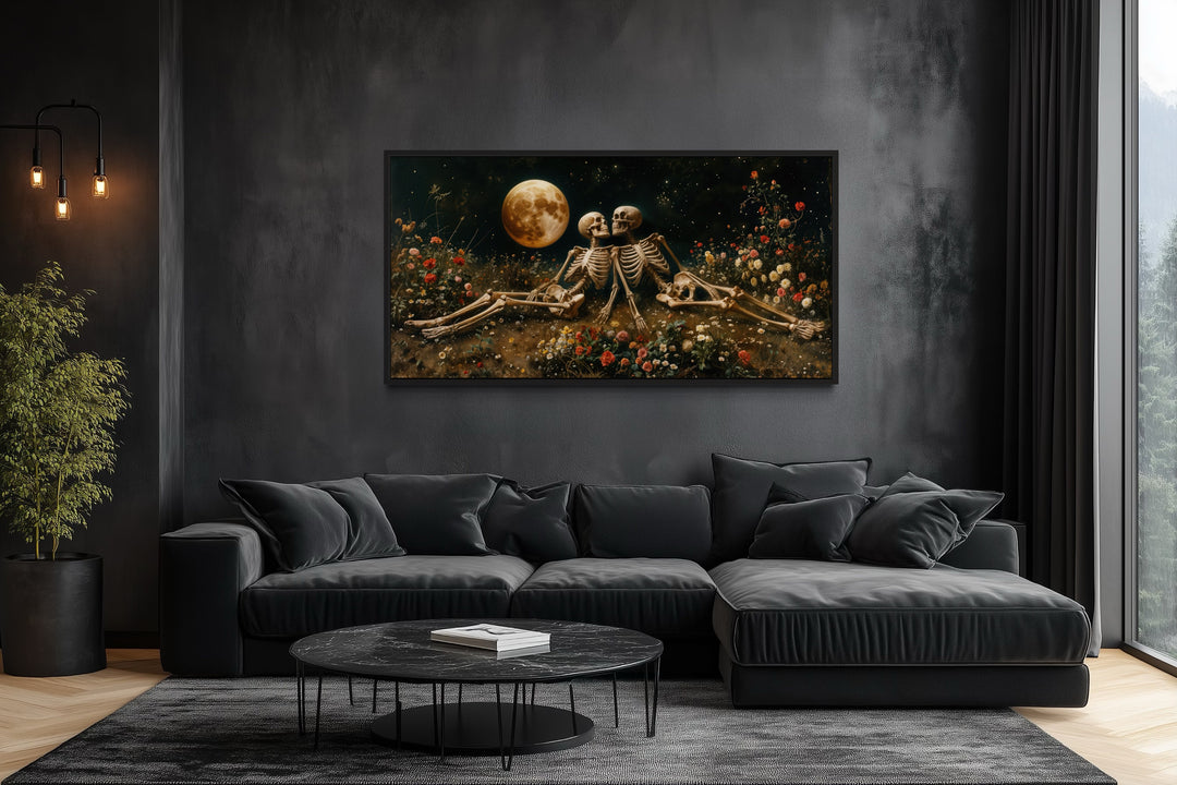 Gothic wall art of two skeletons in a flower meadow under a full moon above a black sofa.